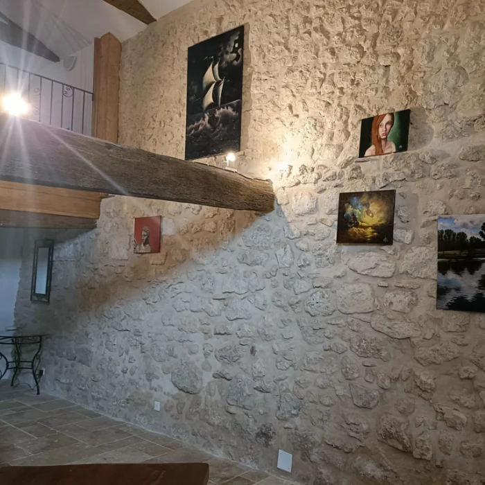 Mur en pierres apparentes avec tableaux à l'huile et poutres apparentes