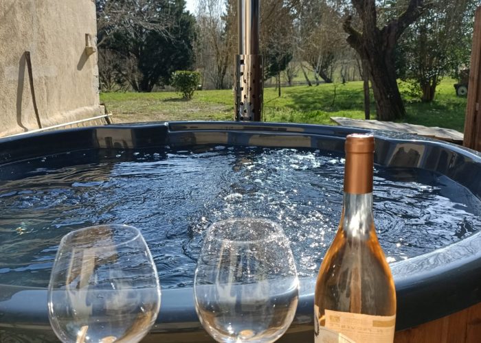 Une bouteille de rosée et deux verres de vin avec le bain nordique en arrière-plan