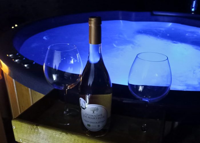 Le bain nordique de nuit avec deux verre à vin et une bouteille de rosée