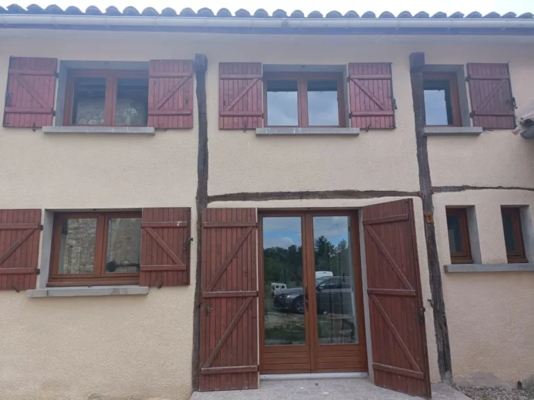 La façade du gîte avec les volets rouges ouverts