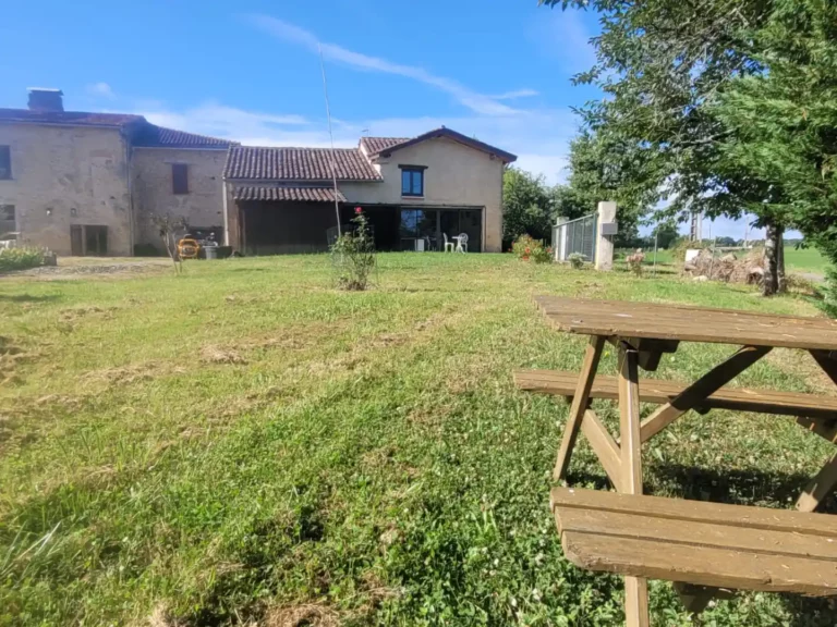 La table de piquenique dans le champ avec le gîte en arrière-plan