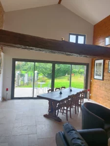 Le Grand Castillon Logement - gîte La table du salon et vue sur l'extérieur par la grande baie vitrée lumineuse